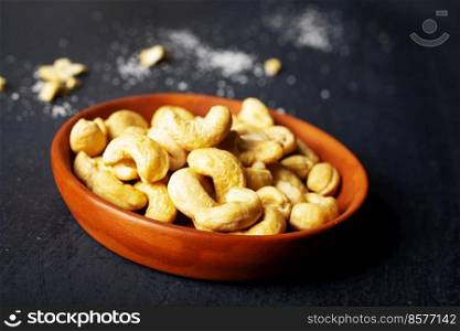 Tasty cashew nuts in bowl on dark table, top view. cashew nuts in bowl on dark table, top view