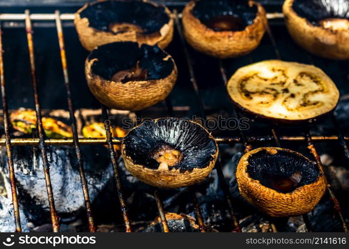 Tasty champignon mushrooms and veggies being cooked on charcoal grill