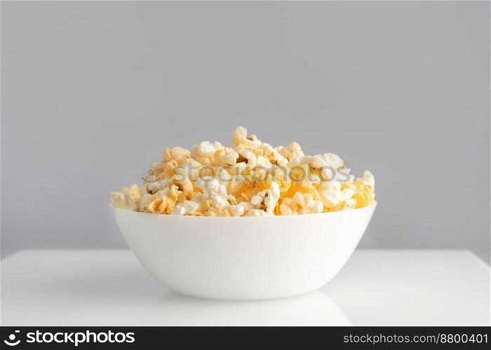 Tasty cheese popcorn in bowl isolated on white background close up. Movies, cinema and entertainment concept.