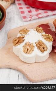 Tasty cheese with walnuts on chopping board