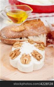 Tasty cheese with walnuts on chopping board