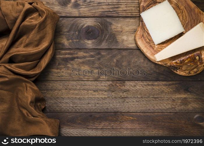 tasty cheese wooden cheese board with brown silk fabric old wooden surface. High resolution photo. tasty cheese wooden cheese board with brown silk fabric old wooden surface. High quality photo