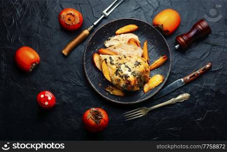 Tasty chicken meat roasted with persimmon. Chicken breast baked with fruit on the plate. Chicken meat fried with persimmon