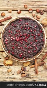 Tasty chocolate cake with pomegranate on a wooden background.. Chocolate cake with pomegranate