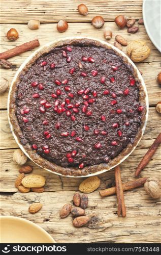 Tasty chocolate cake with pomegranate on wooden background.. Chocolate cake with pomegranate