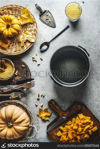 Tasty cooking preparation with various pumpkins, cooking pot, kitchen utensils and spices at grey concrete table. Seasonal autumn vegetables. Top view.
