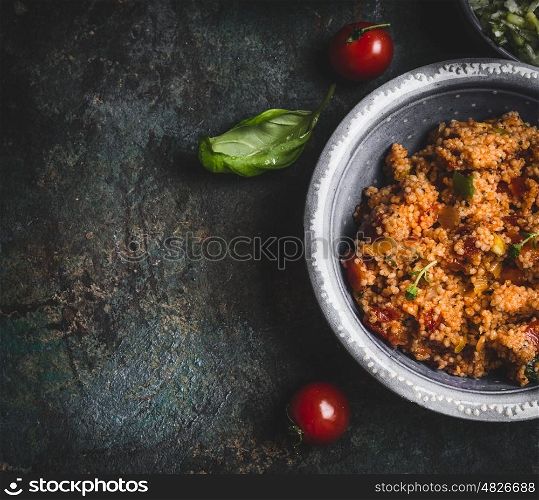 Tasty couscous salad in bowl on dark rustic background, top view, close up, border. Healthy eating, Vegetarian or vegan food concept