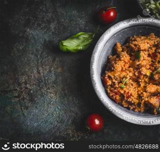 Tasty couscous salad in bowl on dark rustic background, top view, close up, border. Healthy eating, Vegetarian or vegan food concept