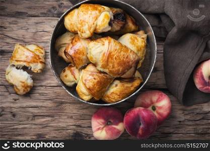Tasty croissants with peaches. Rural homemade croissants with peaches on a retro table