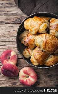Tasty croissants with peaches. Rural homemade croissants with peaches on a retro table