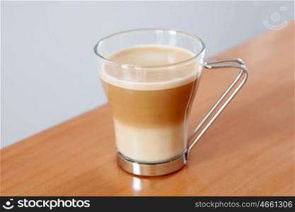 Tasty cup of coffee with milk on a wooden table