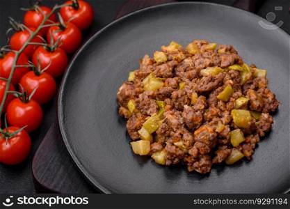 Tasty dish consisting of zucchini, beef meat, mushrooms, onions and garlic with salt and spices on a dark concrete background