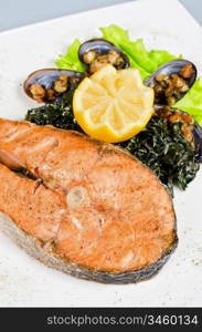 Tasty dish of salmon steak with algae mussels, lemon and kiwi