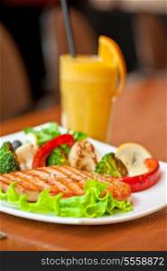 Tasty dish of salmon steak with vegetables and juice