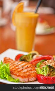 Tasty dish of salmon steak with vegetables and juice