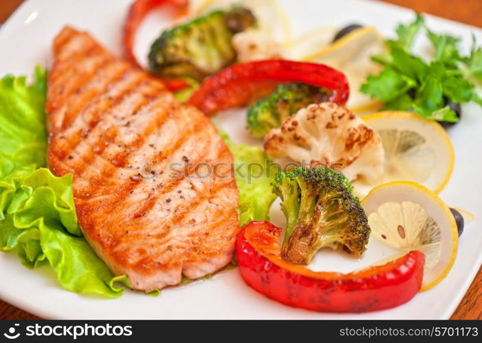 Tasty dish of salmon steak with vegetables and juice