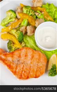 Tasty dish of salmon steak with vegetables and sauce
