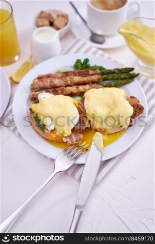 Tasty eggs Benedict, hollandaise sauce and aspargus covered with bacon.. Tasty eggs Benedict, hollandaise sauce and aspargus covered with bacon