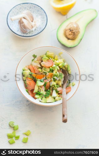 Tasty fresh avocado tomato salsa salad on white kitchen table background, top view. Healthy food. Vegetarian lunch or snack