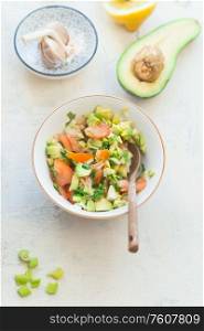 Tasty fresh avocado tomato salsa salad on white kitchen table background, top view. Healthy food. Vegetarian lunch or snack