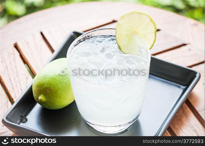 Tasty fresh lime juice with lime on wood table