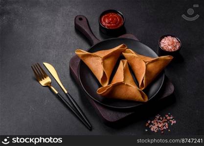 Tasty fresh pancakes with meat, sheep, spices and herbs on a dark concrete background. Tasty fresh pancakes with meat, sheep, spices and herbs