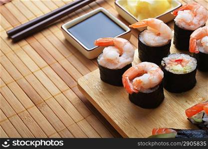 tasty fresh sushi rolls on wooden plate