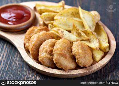 Tasty fried nuggets and potatoes on a table. Tasty fried nuggets and potatoes