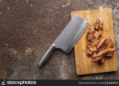 tasty fried pork fillet with knife in wooden cutting board on rusty texture background with copy space for text, top view