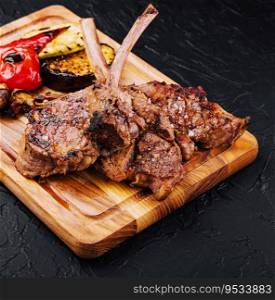Tasty grilled lamb ribs with vegetables on board