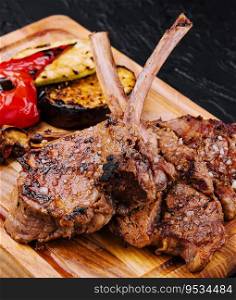 Tasty grilled lamb ribs with vegetables on board