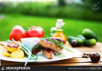 tasty grilled meat sausages on dish and vegetable