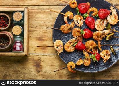 Tasty grilled shrimps on wooden skewers with strawberries.Roasted prawns,seafood. Grilled shrimps on skewers with strawberries,BBQ shrimp