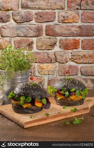 Tasty grilled veggie burger with lentils, dry tomato and thyme with black bread on wooden countertop.