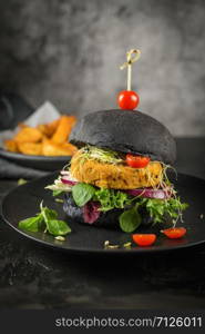 Tasty grilled veggie burgers with chickpeas and vegetables on black bread on dark wooden countertop.