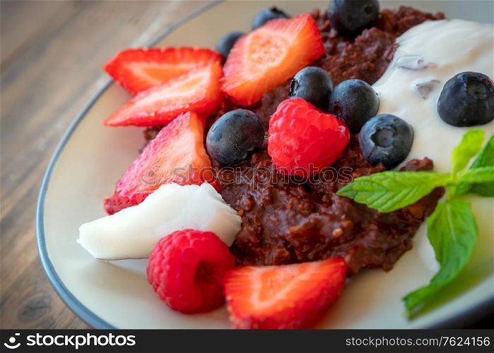 Tasty healthy breakfast, fresh juicy fruits and berries on the plate with yogurt and granola, delicious vegetarian food, organic diet nutrition