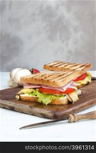 Tasty healthy sandwiches at white wooden table. Rustic style. . Tasty healthy sandwiches with mushrooms and tomatoes and knife with wooden handle at cutting board on white wooden table