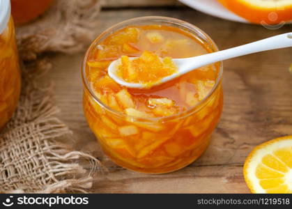 Tasty homemade orange jam and slice of orange fruit on the wooden table.