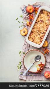Tasty homemade peach cobbler with ingredients , plate and spoon on light background. Top view