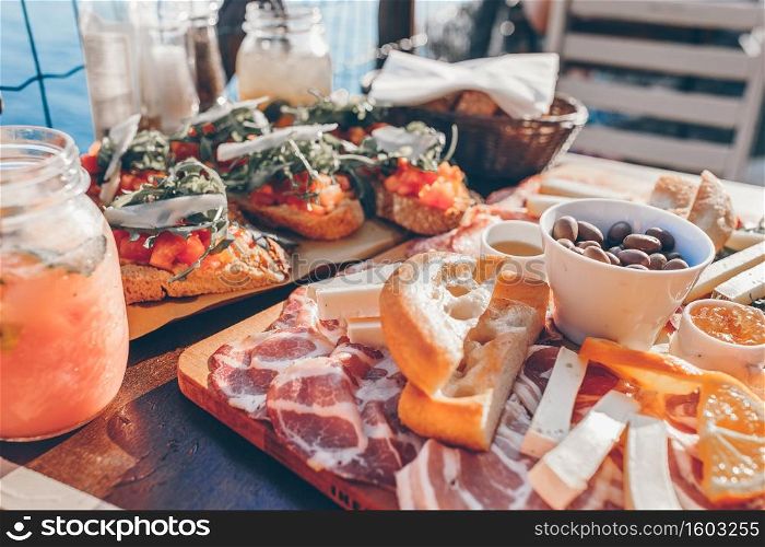 Tasty italian snacks. Fresh bruschettes, cheeses and meat on the board in outdoor cafe with amazing view in Manarola, Italy. Fresh bruschettes, cheeses and meat on the board in outdoor cafe with amazing view in Manarola