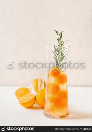 Tasty lemonade with orange juice ice cubes and rosemary in glas jug . Refreshing summer drink