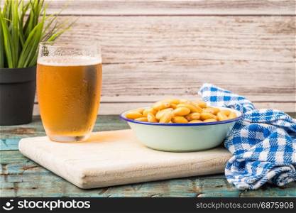 Tasty lupins in metal mug and glass of beer on wooden table top.