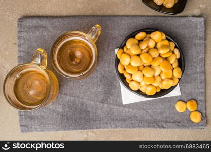 Tasty lupins in metal mug and glass of beer on wooden table top.