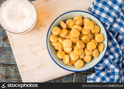 Tasty lupins in metal mug and glass of beer on wooden table top.