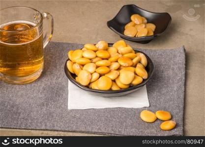 Tasty lupins in metal mug and glass of beer on wooden table top.