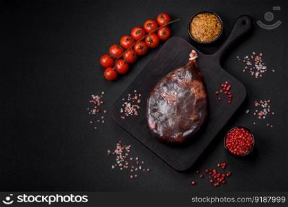 Tasty mahan, prosciutto or jamon on a wooden cutting board on a dark concrete background