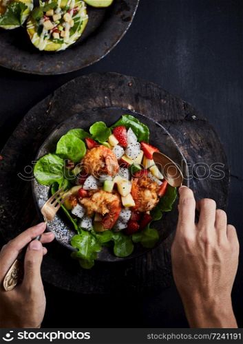 Tasty meal with fresh and healthy prawn salad and vegetables on dark background.. Fruit salad.