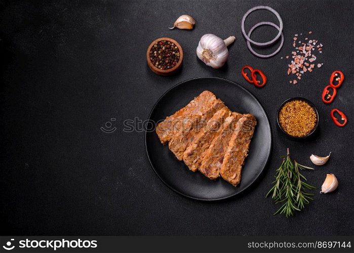Tasty meat brawn or roll on a wooden cutting board with spices and herbs on a dark concrete background. Tasty meat brawn or roll on a wooden cutting board with spices and herbs
