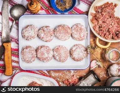 Tasty Meat patties cooking preparation in enamelled bowl with kitchen knife and ingredients on rustic background, top view