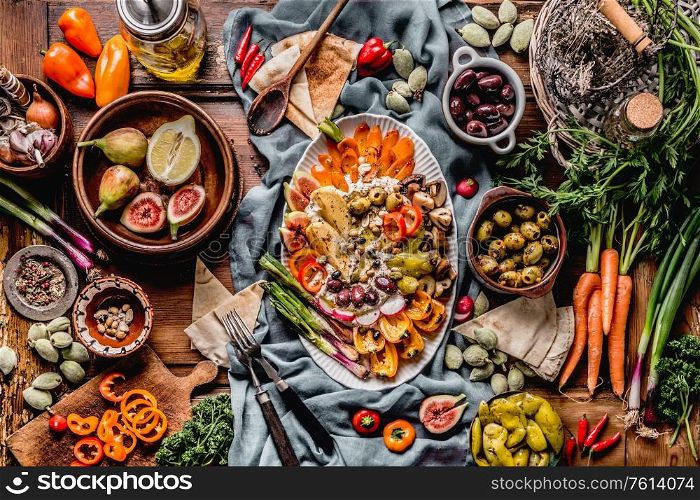 Tasty Mediterranean cuisine with healthy food with hummus plate. Ramadan iftar dinner. Various pickled and fresh vegetables: olives, fids, green almond. Vegan party food Top view. Festive gathering